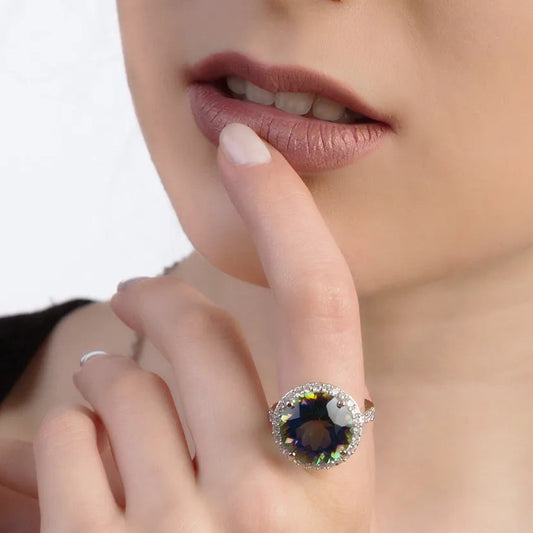 Close-up of a hand wearing a ring with a blue gemstone on a white background