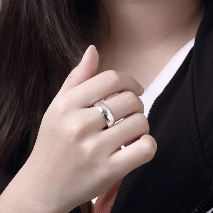 Close-up of a hand wearing a silver ring with a blurred background