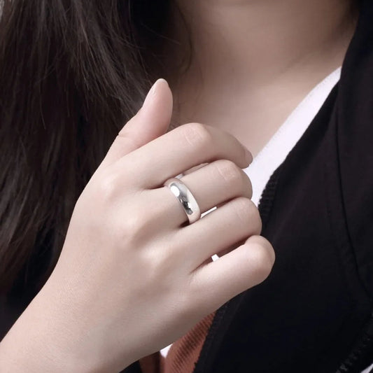 Close-up of a hand wearing a silver ring with a blurred background