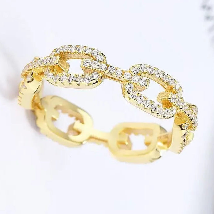 Gold chain-style ring with clear stones on a light background