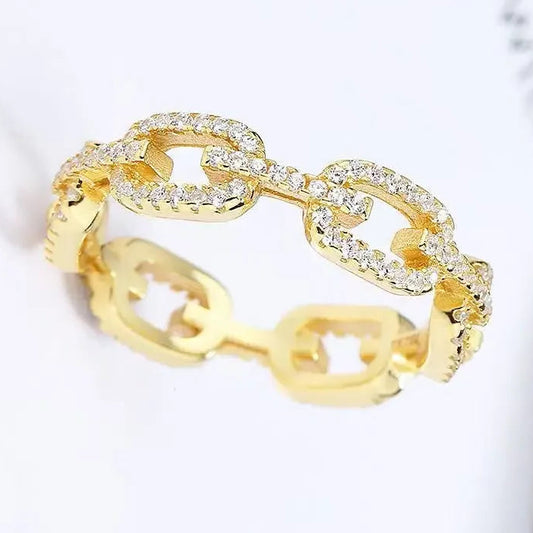 Gold chain-style ring with clear stones on a light background