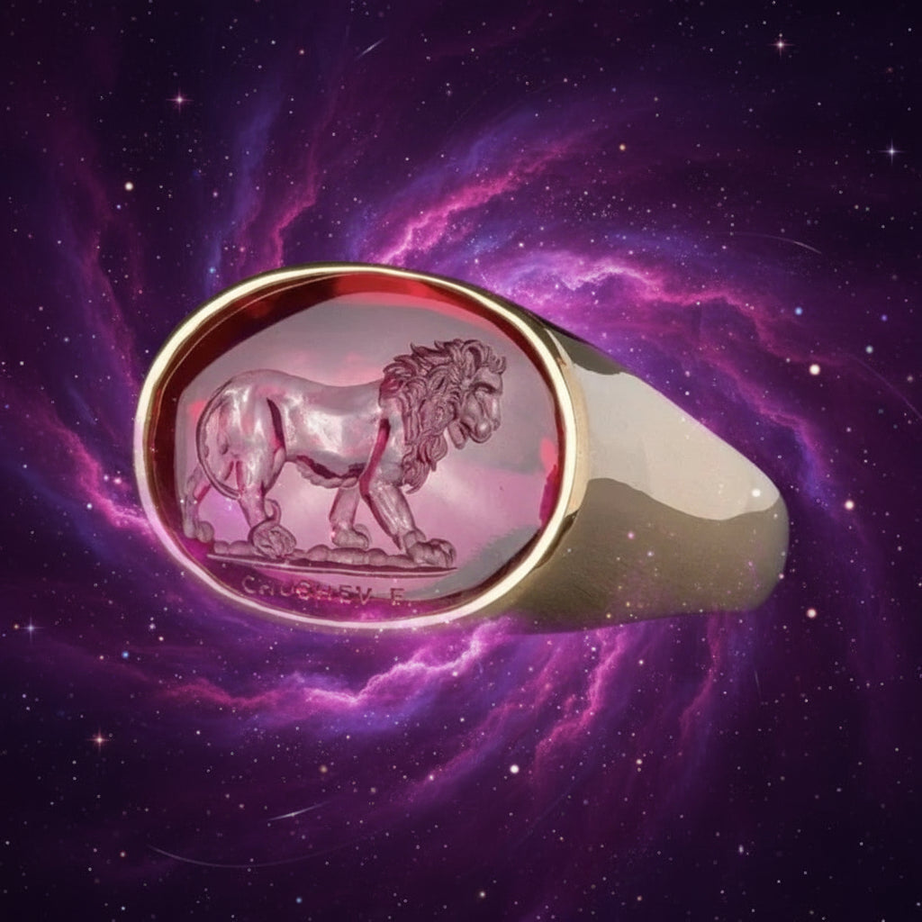 Gold ring with a pink stone featuring a lion emblem on a gray background