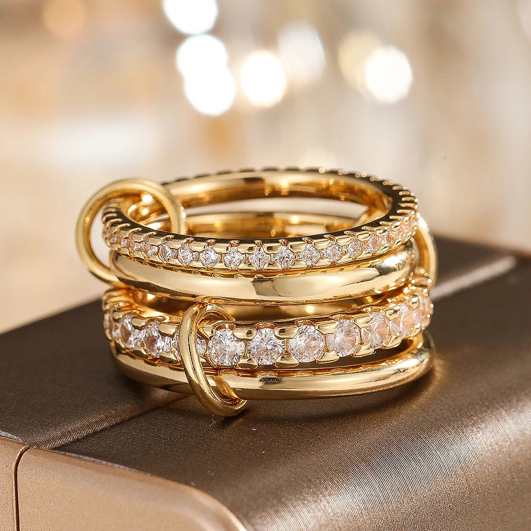 Three gold rings with diamond accents on a reflective surface with a blurred background