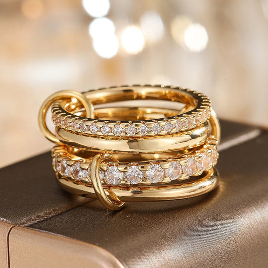 Three gold rings with diamond accents on a reflective surface with a blurred background