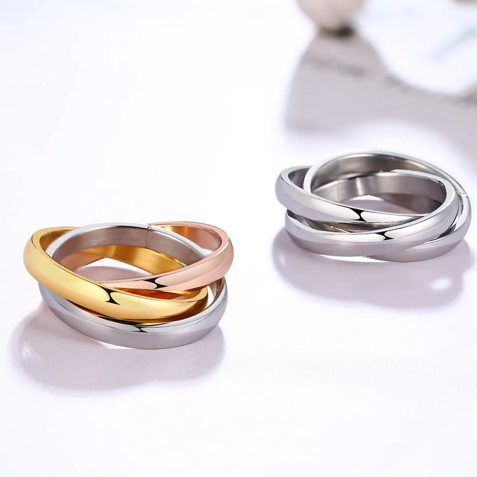 Three interlocking rings in gold, silver, and rose gold on a white background